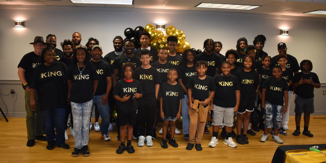 Group photo of diverse people wearing matching KING t-shirts indoors.