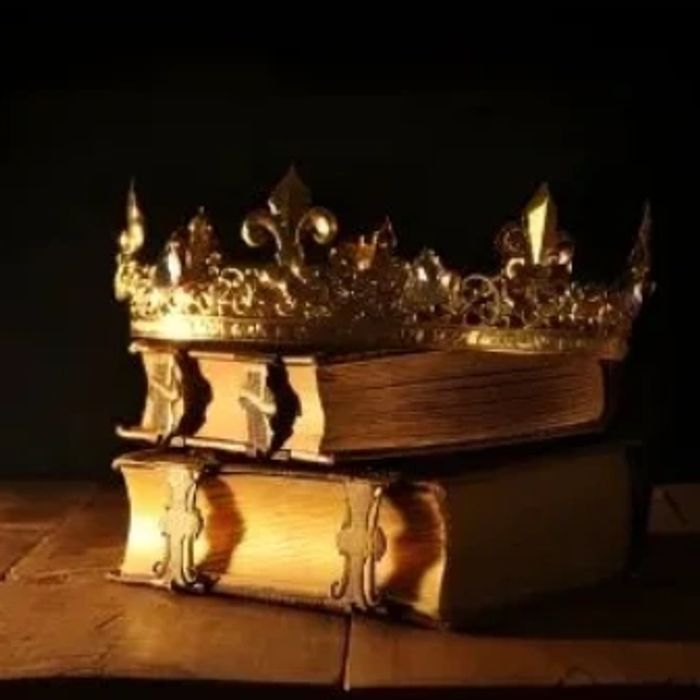 Golden crown resting on two old books on a wooden surface.