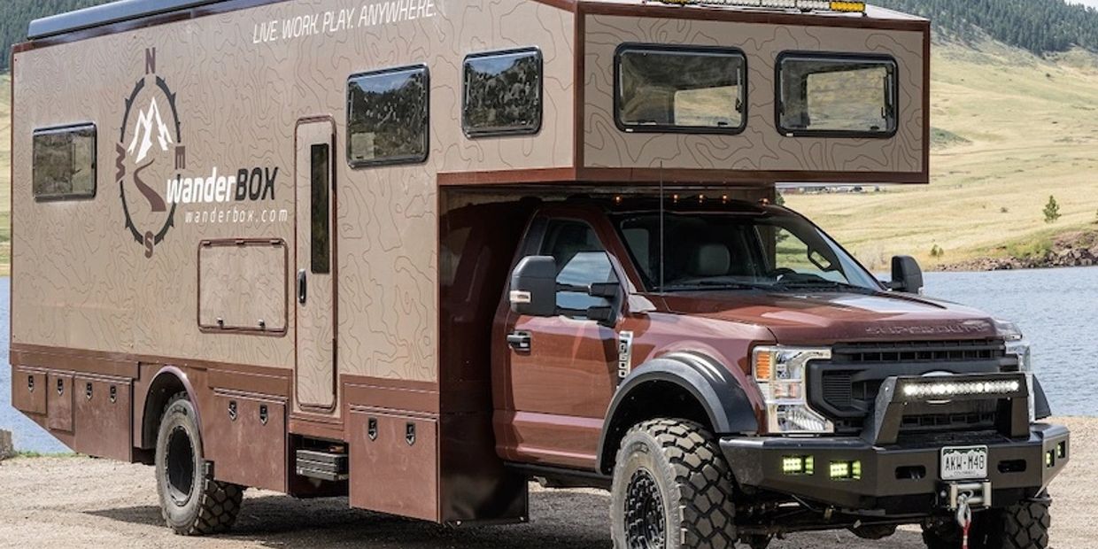 A rugged brown wanderBOX camper truck parked near a lake.