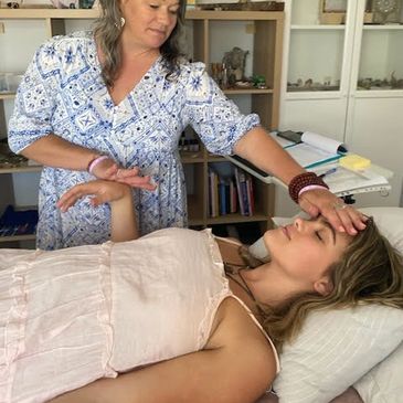 child laying down on massage bed woman muscle testing childs arm for kinesiology remedies