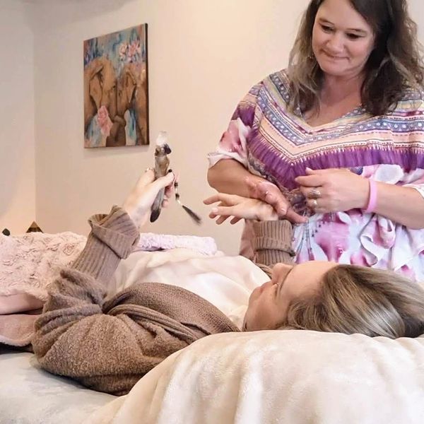 mel kinesiologist muscle testing a client laying on the massage table holding a remedy the wand 