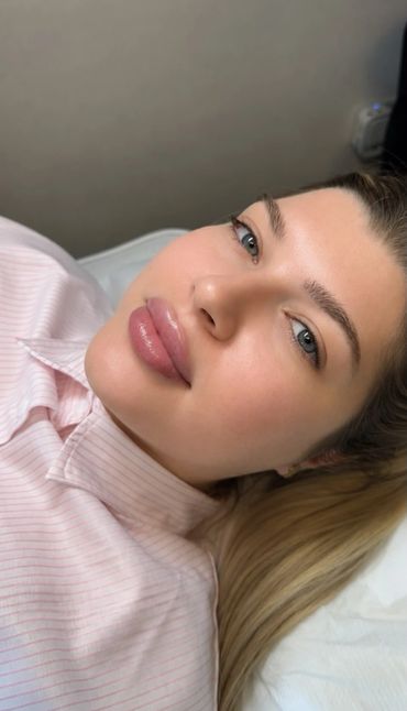 Close-up of a woman lying down with flawless skin and glossy lips.