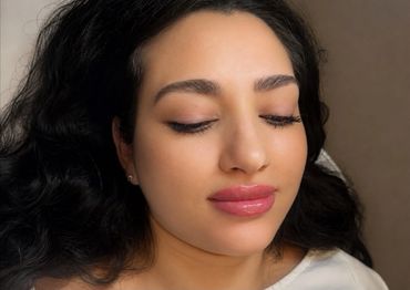 Close-up of a woman with glossy pink lips and closed eyes.