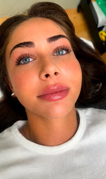 Close-up of a young woman with blue eyes and glossy lips.