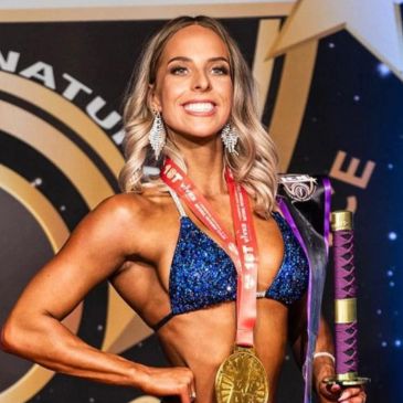 Smiling female athlete with medal and trophy.