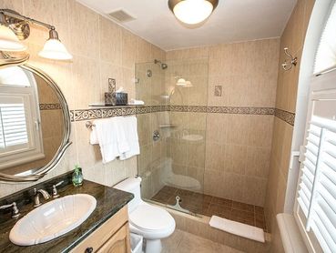 Modern bathroom with glass shower and granite countertop.