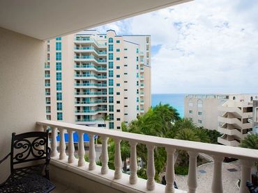 View from a balcony overlooking buildings and the ocean.