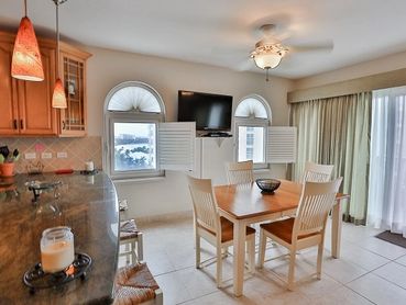 Cozy dining area with table, chairs, and a TV on the wall.