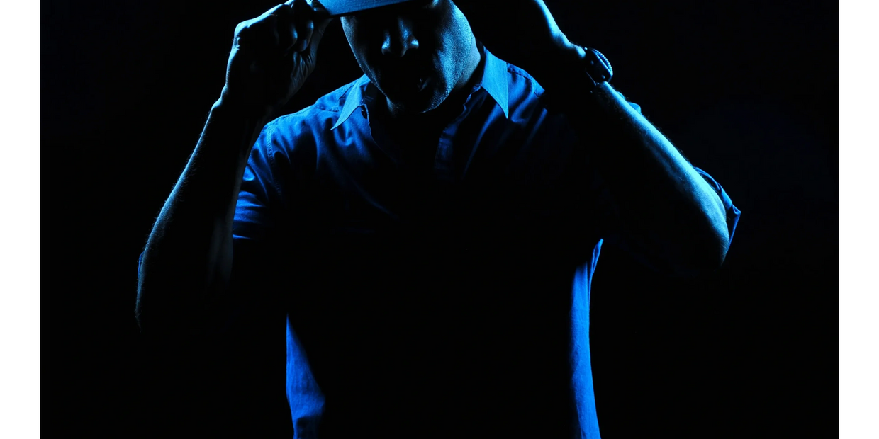 Image of Owner and photographer, holding the brim of hat, staring into camera.