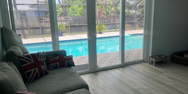 Living room with a sofa facing a glass pool door and Union Jack pillows.