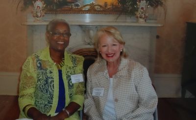 Two women smiling and seated indoors.