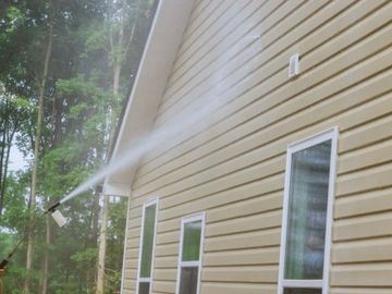 A person power washing the exterior siding of a house.