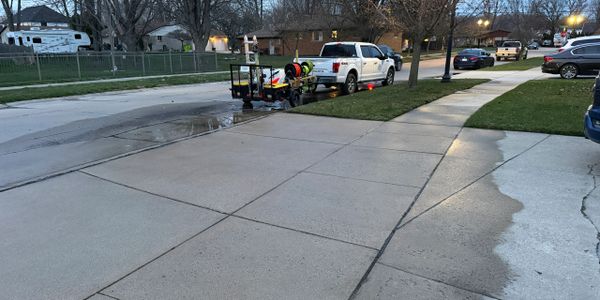 A clean driveway with water and cleaning equipment beside a white truck.