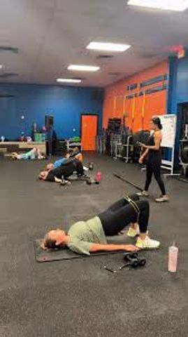People exercising in a gym with instructor guidance.
