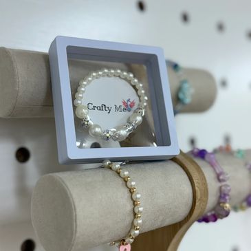 Elegant pearl bracelets displayed on a beige velvet stand with a branded box.