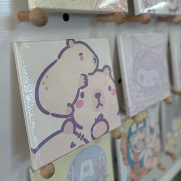 Close-up of cartoon canvases displayed on wooden peg wall.
