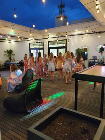 Women dancing in a decorated outdoor space under string lights at night.