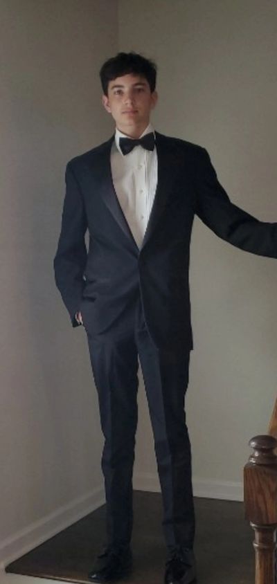 Young man dressed in a classic black tuxedo with a bow tie.