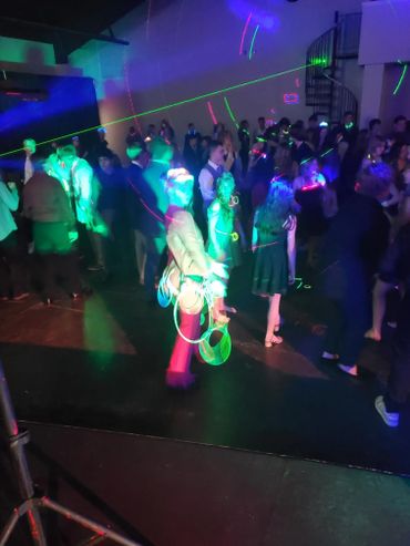 People dancing under colorful laser lights in a dark room party.