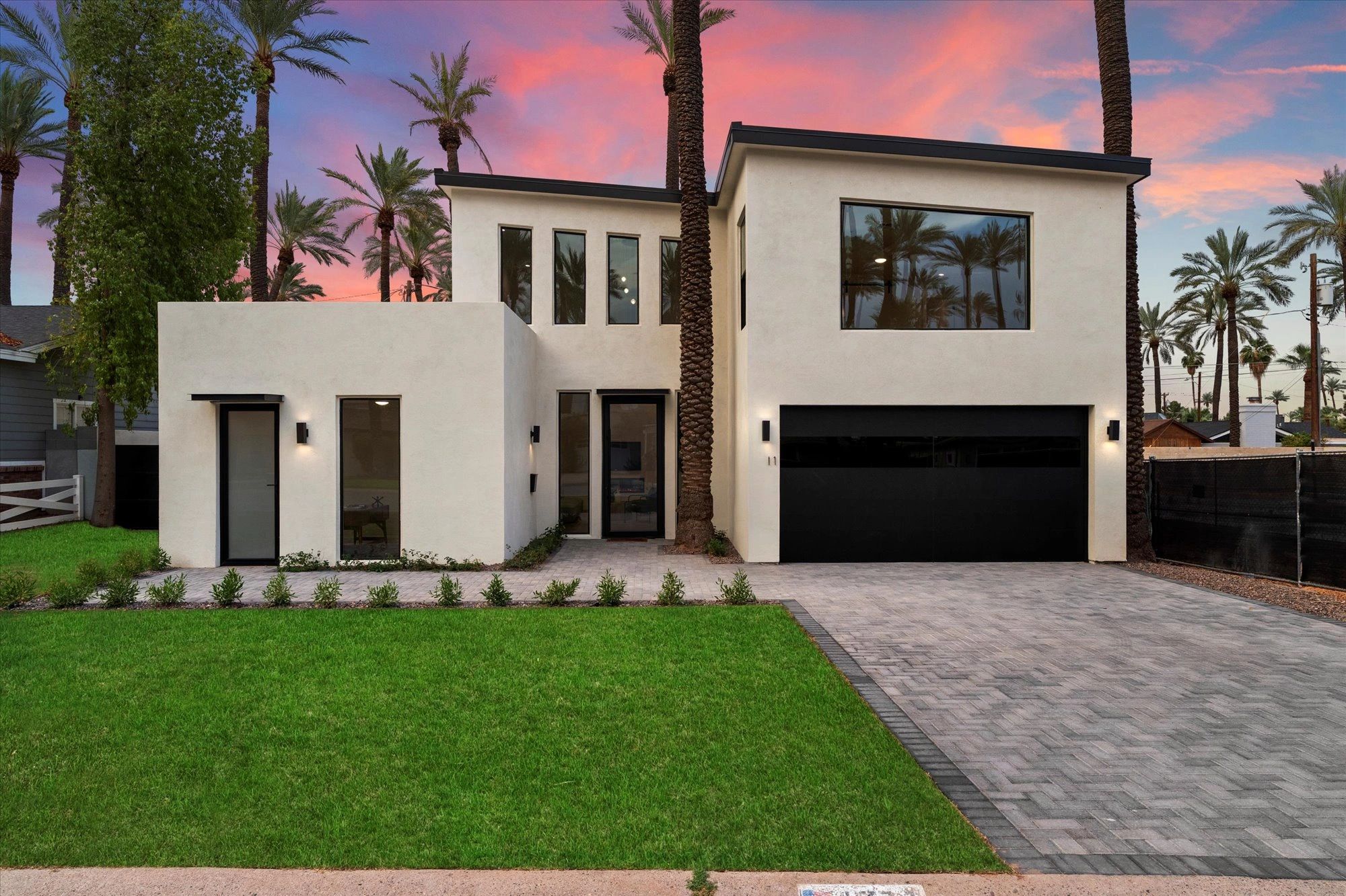A charming gray house on a grassy hill by the ocean under a clear blue sky.