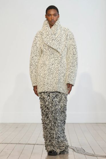 Model wearing a textured cream jacket and black-and-white shaggy skirt.