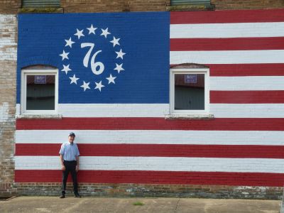 Man standing in front of a painted American flag mural.