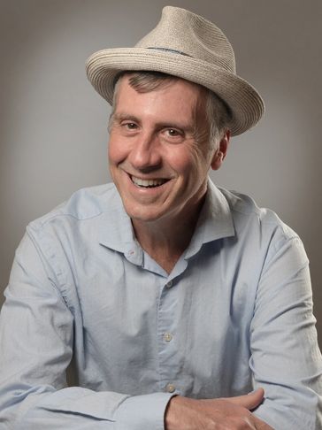 Smiling man wearing a light blue shirt and beige hat.