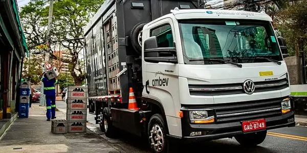 A white Volkswagen delivery truck parked on the street unloading crates.