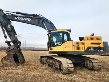 Yellow Volvo excavator in a dry field.