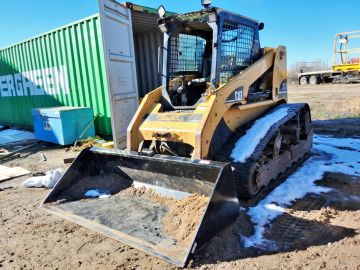 Caterpillar skid steer loader with snow on tracks.