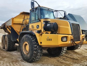 Large yellow dump truck on dirt ground.