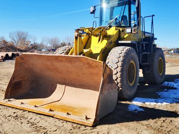 Yellow front loader parked on dirt.