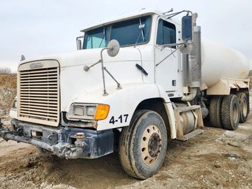 White cement mixer truck parked on a dirt road.