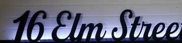 Illuminated decorative sign reading '16 Elm Street' in cursive lettering.