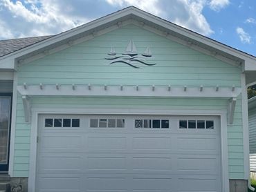 Light blue house with a white garage door and sailboat wall decor.