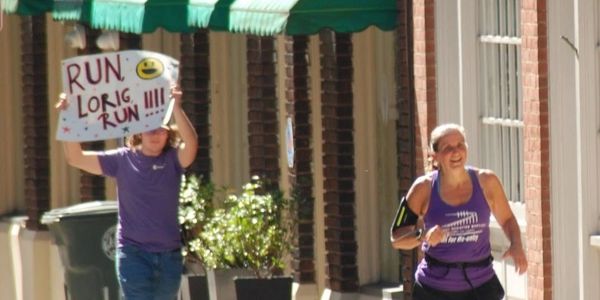Woman running, another holding a supportive sign.