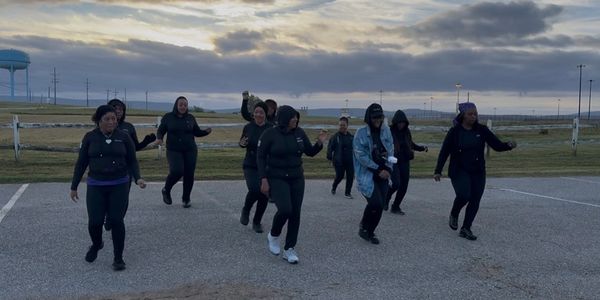 Group of people dancing outdoors at sunset.