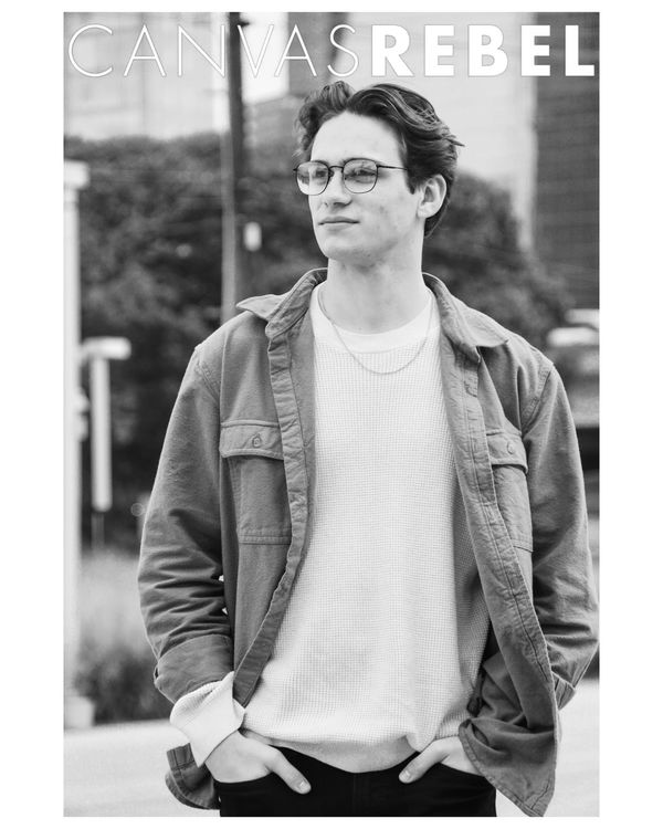 Black and white photo of a young man in glasses and casual jacket.