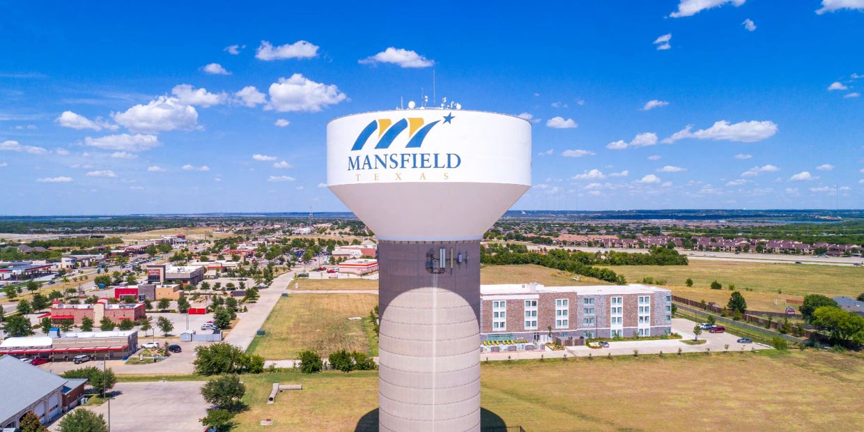 Water tower in Mansfield, Texas under a blue sky.