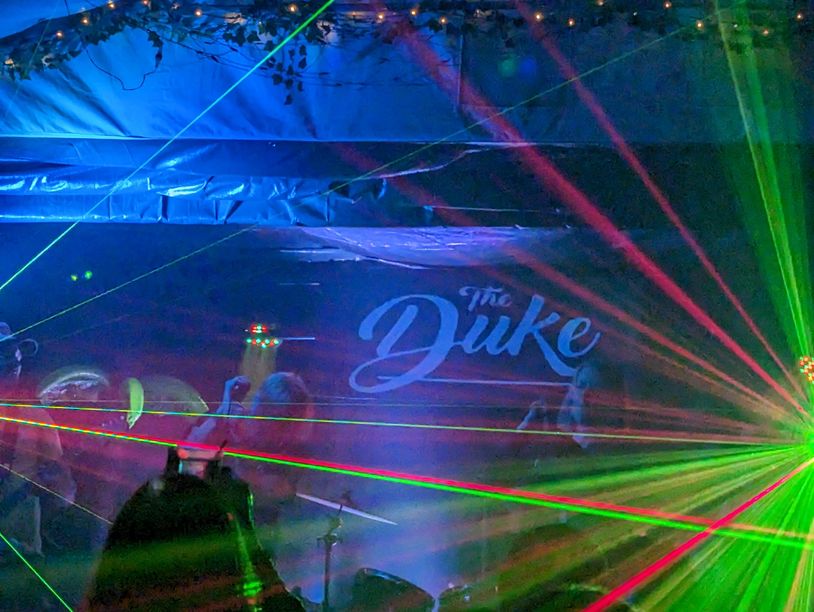 A vibrant laser light show at The Duke nightclub with people dancing.