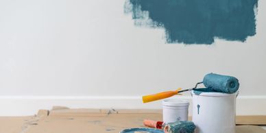 Interior wall painting in progress with professional tools and blue paint.