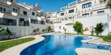 Resort pool area surrounded by white buildings.