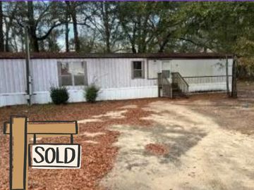 Mobile home with a sold sign in front.