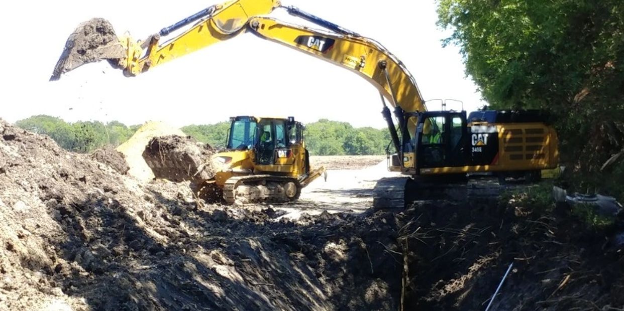 Two yellow excavators moving soil at a construction site.