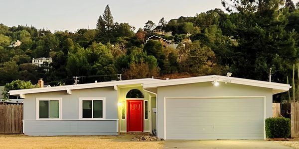 Single-story house with a bright red door and two-car garage at dusk.