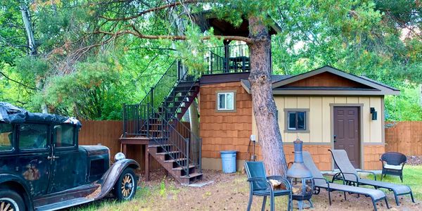 Vintage car next to a wooden shed with outdoor furniture.
