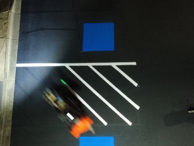 Blurred person walking across a marked street crossing at night.