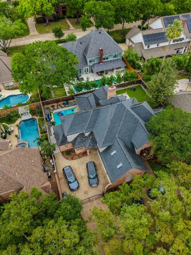 Aerial view of a suburban house with a driveway and swimming pool.