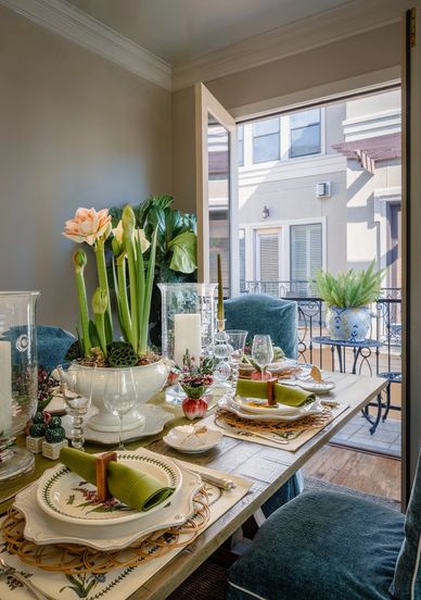 Elegant dining table set with floral centerpiece and green napkins in a cozy room with balcony view.