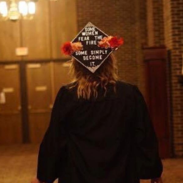 girl with graduation cap that reads "some women fear the fire, some simply become it"